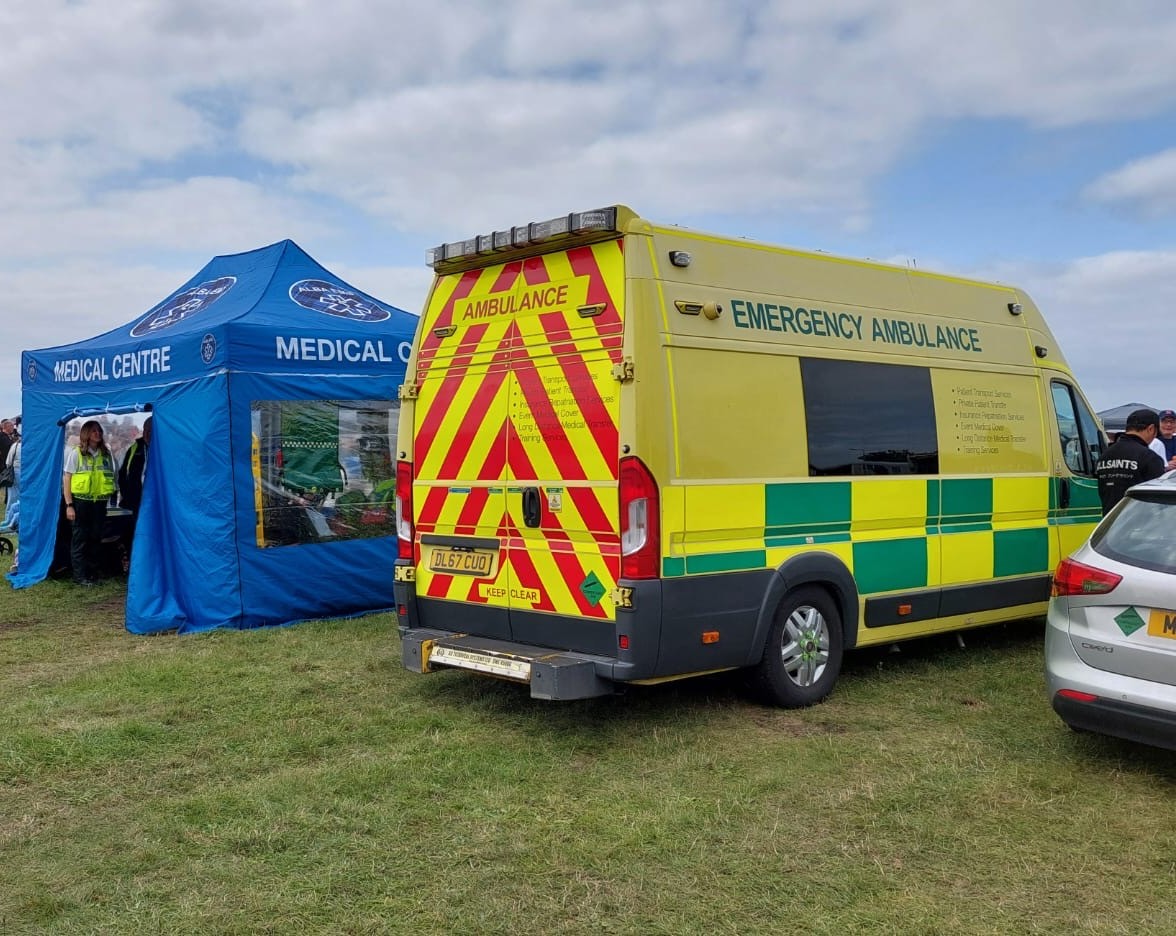 Alba EMS emergency ambulance and blue medical centre tent pitched on the grass at an outdoor event