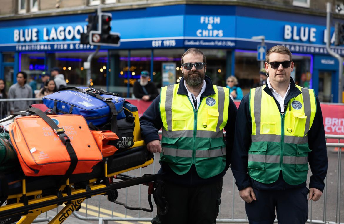 Two Alba EMS paramedics on duty in high-visibility vests at a town-centre event